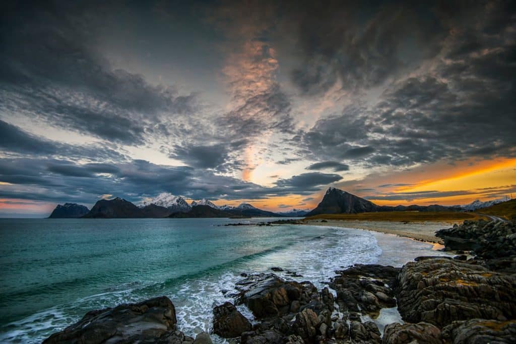 Breathtaking view of a sunset over Nordlands rocky coast with snowy mountains in Norway.